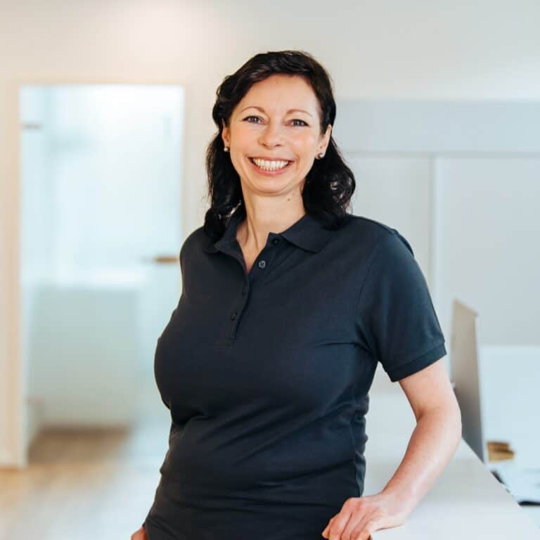 Lächelnde Frau in dunklem Poloshirt und mit dunklen Haaren.