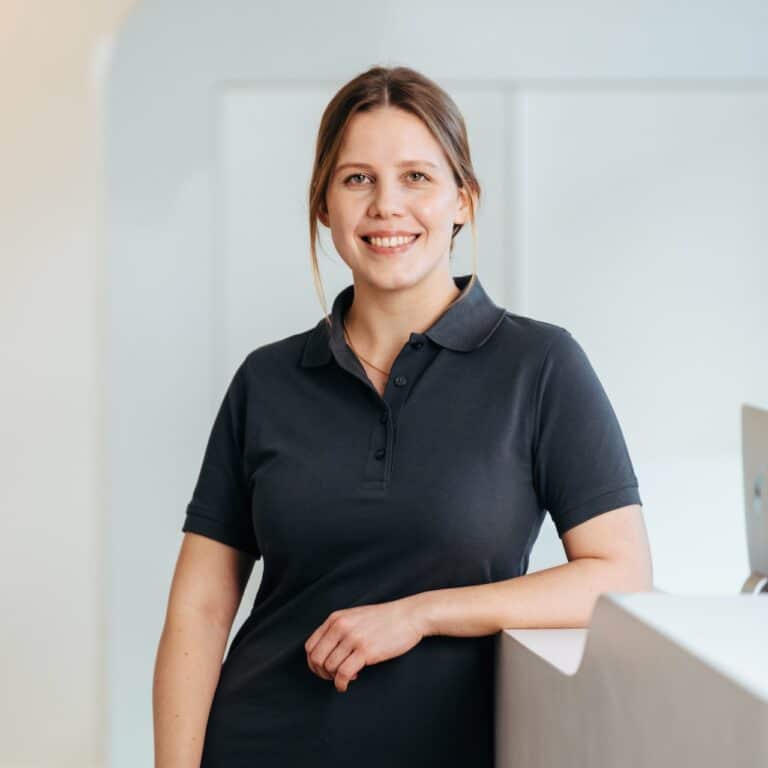 Lächelnde Frau im dunklen Poloshirt in Praxis.