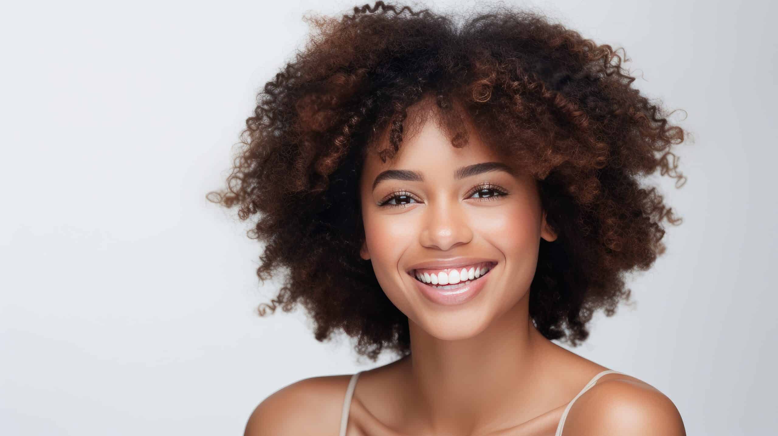 Lächelnde schwarze Frau mit perfekten, strahlend weißen Zähnen nach einem Bleaching.